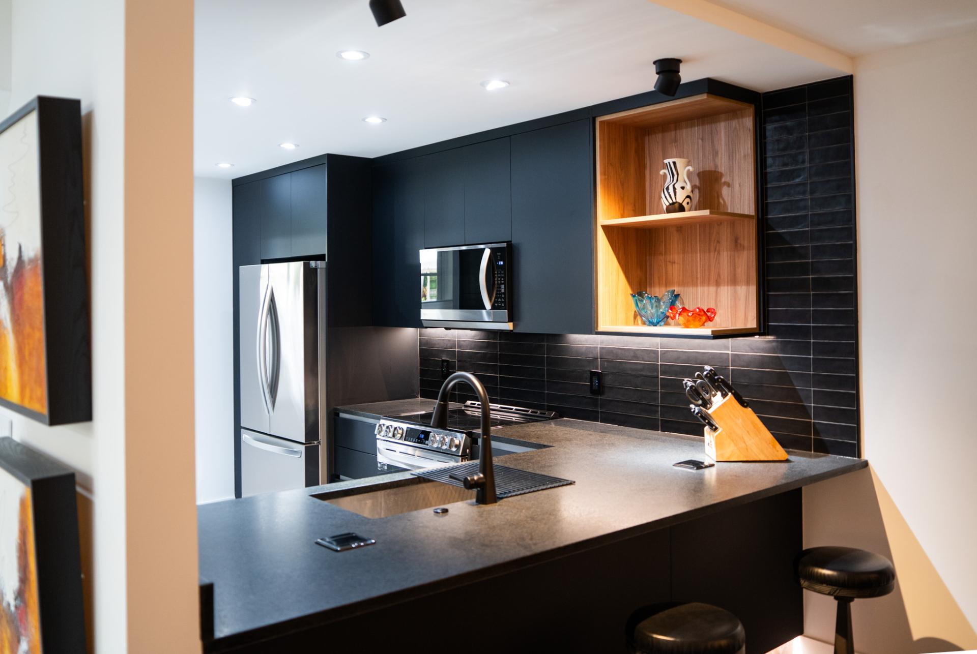Dark custom kitchen cabinetry with illuminated wood display shelving